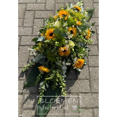 Langwerpig rouwarrangement van o.a. zonnebloemen